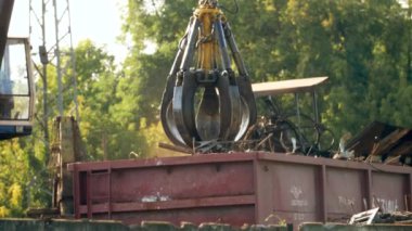 4k video of industrial grip manipulator used for loading and moving iron scrap on scrapyard. Concept of metal recycling on junkyard