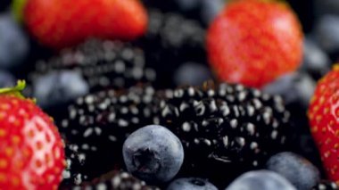 Masada duran böğürtlen ve böğürtlenli böğürtlenlerin üzerinden kayan kameranın makro 4k videosu. Organik gıda ve sağlıklı beslenme için mükemmel soyut bir arka plan..