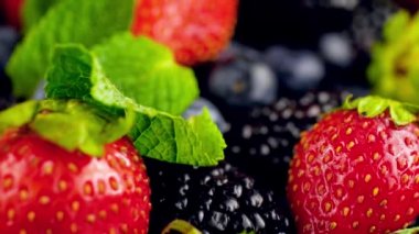 Masada bir sürü böğürtlen ve nane yaprağı üzerinde uçan kameranın 4K görüntüsü. Organik gıda ve sağlıklı beslenme için mükemmel soyut bir arka plan..