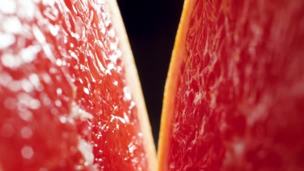 Makro 4k video kamery pohybující se mezi dvěma polovinami řezaného grapefruitu proti černému backgorundu. Perfektní abstraktní snímek pro organické potraviny a zdravou výživu.