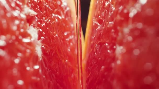 4k macro video van het gieten van water en vallende druppels op gesneden in de helft van verse smakelijke grapefruit. Perfect abstract shot voor biologisch voedsel en gezonde voeding. — Stockvideo