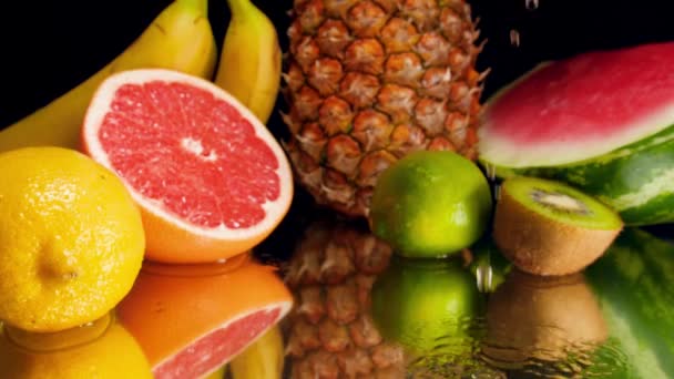 Nahaufnahme-Zeitlupenvideo von Kokosnuss mit Kokosmilch, die neben tropischen Früchten vor schwarzem Hintergrund fällt. Perfekte abstrakte Aufnahme für Bio-Lebensmittel und gesunde Ernährung. Nahaufnahme von tropischen — Stockvideo