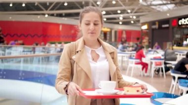 4k video of beautiful smiling woman walking in self service cafe with food on plastic tray