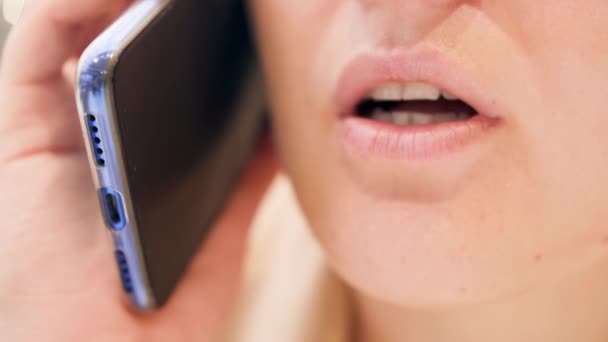 Close up 4k video of female lips moving while talking by phone. Женщина серьезно разговаривает — стоковое видео