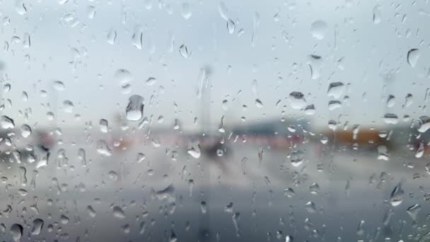 Gros plan vidéo 4k à travers hublot d'avion recouvert de gouttelettes d'eau sur le terminal de l'aéroport à la tempête de pluie — Video