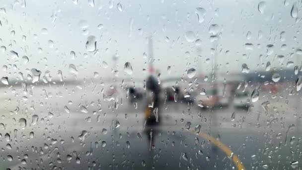 Vídeo 4k a través de ventana húmeda en aviones mojados y terminal del aeropuerto durante tormenta de lluvia — Vídeo de stock