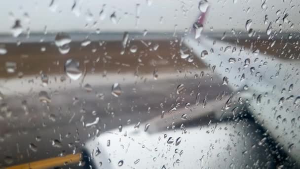 4k video genom flygplansfönstret täckt med regn sovsalar av flygplan som kör på banan under kraftiga regn storm — Stockvideo