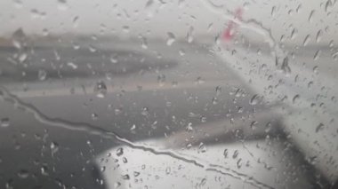 Fırtınada ıslak pistten kalkış sırasında uçak camında akan yağmur suyu akışının 4k videosu