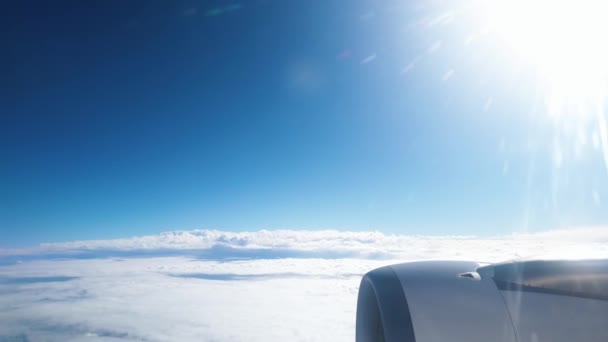 4k video of airplane engine and wing flying above the clouds in clear blue sky — Stock Video