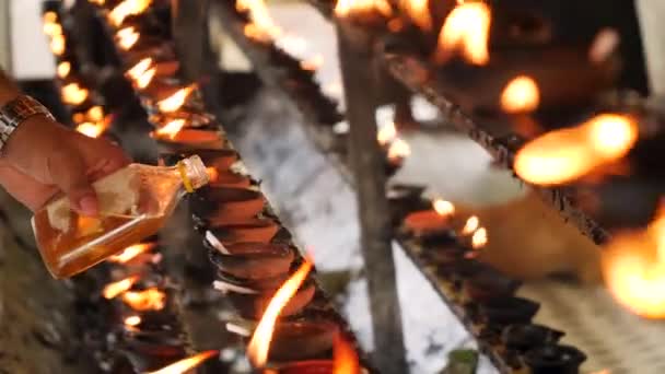 Primer plano 4k video de adorador vertiendo aceite sagrado en lámpara ardiente en el altar del templo budista — Vídeo de stock