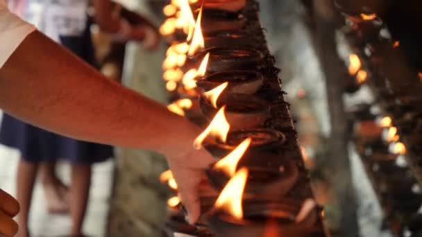 4k closeup vídeo de adoração de pessoas acendendo lâmpadas de óleo em chamas no templo budista no Sri Lanka — Vídeo de Stock