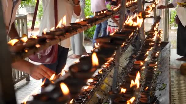 4k видео, где буддисты поклоняются людям, светящимся и кладущим горящие масляные лампы на алтарь в буддийском храме — стоковое видео
