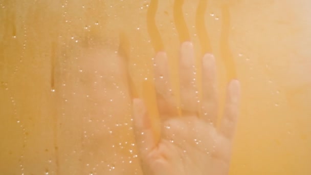 Nahaufnahme 4k Video einer weiblichen Hand, die in der Dusche vernebeltes Glas berührt — Stockvideo