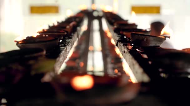 Closeup 4k video of long rows of burning candles and oil lamps on the altar of buddhist temple — Stock Video