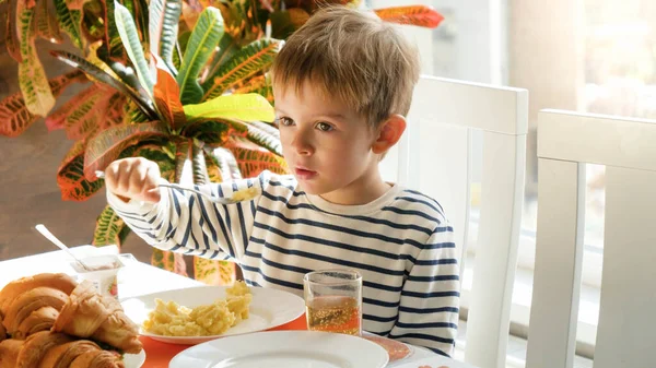 Portrait of little boy eating porridge or mashed potate in dining room — Stock Photo, Image