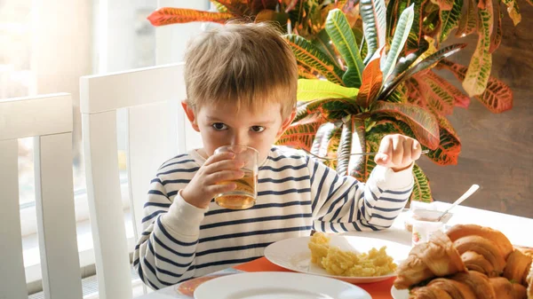 Küçük şirin bir çocuğun portresi yemek odasında reakfast içerken meyve suyu içiyor. — Stok fotoğraf