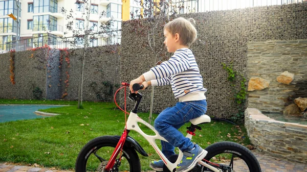 Feliz niño sonriente montando su primera bicicleta en el parque — Foto de Stock