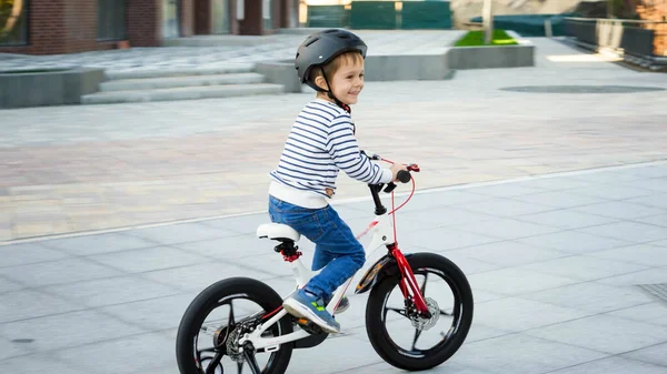 Joyeux garçon souriant chevauchant rapidement son vélo sur la rue de la ville — Photo