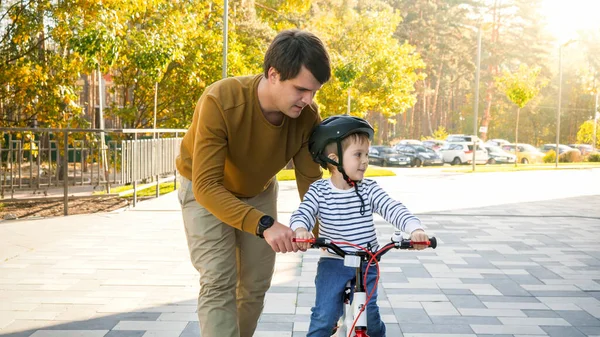 Portret mężczyzny i jego syna jadących na rowerze ulicą miasta w słoneczny dzień — Zdjęcie stockowe