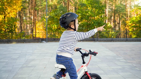 Niño feliz montando su bicicleta y señalando con el dedo índice — Foto de Stock