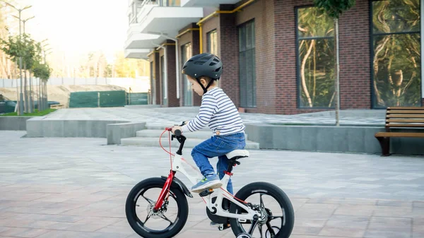 Joyeux petit garçon portant un casque apprenant à monter son premier vélo dans la rue de la ville — Photo