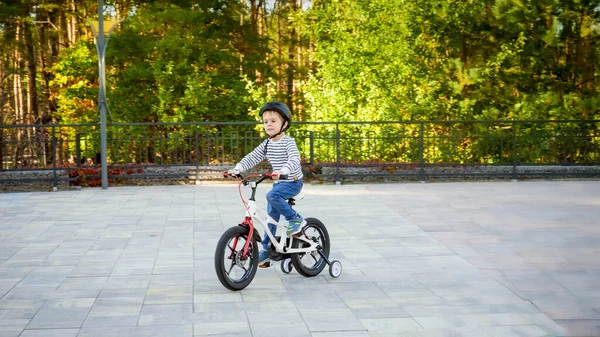 Petit garçon de 3 ans en casque de protection chevauchant sa première bicyclette au parc — Photo