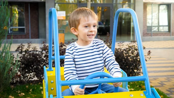 Portret wesołego uśmiechniętego chłopca palącego się w drewnianym samochodzie na placu zabaw — Zdjęcie stockowe