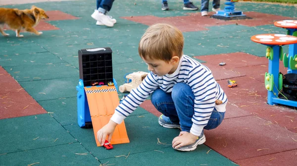Küçük çocuk parktaki çocuk parkında oyuncak arabalarla ve plastikle oynuyor. — Stok fotoğraf