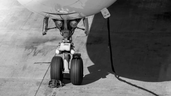 Czarno-biały obraz kabla zasilającego i przedniego podwozia samolotu podczas konserwacji — Zdjęcie stockowe