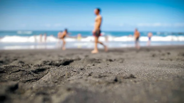 Kalabalık okyanus plajının siyah volkanik kumla bulanık görüntüsü. — Stok fotoğraf