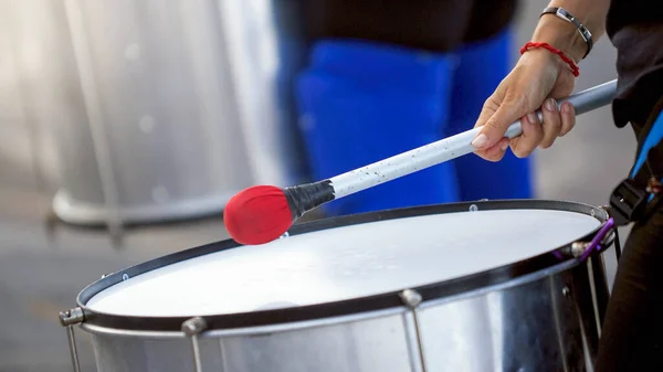 Closeup image of street musician playing on drum with stick during street performance
