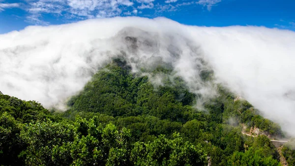 Prachtig landschap van dichte wolken stroomt en bedekt hoge bergtoppen op torpical eiland — Stockfoto