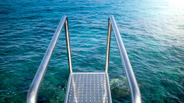 Metal handrails and ladder leading to clear turquoise sea water — Stock Photo, Image