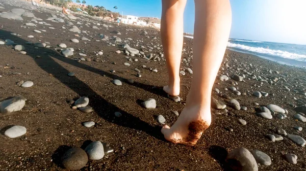Detailní zadní pohled obrázek sexy ženské nohy kráčející pryč na mořské pláži s černým sopečným pískem — Stock fotografie