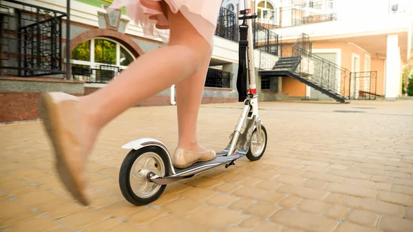 Imagem de close-up de bela jovem mulher na saia andando rápido em chute scooter na rua da cidade — Fotografia de Stock