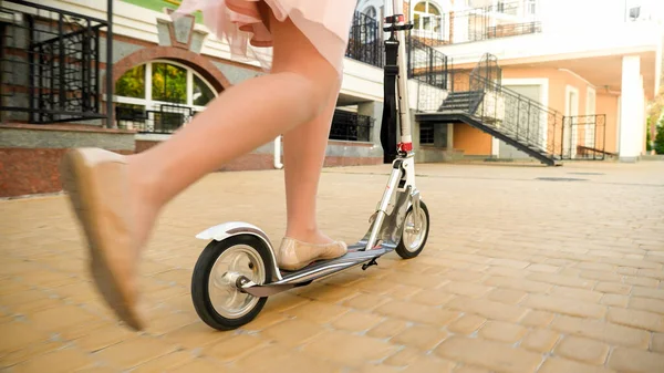 Close-up beeld van mooie jonge vrouw in rok rijden snel op kick scooter op straat — Stockfoto