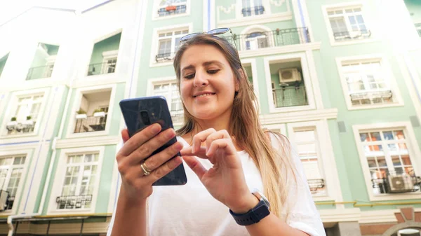 Portrait of happy young girl with smartphone typing message in social medi on smartphone — Stock Photo, Image