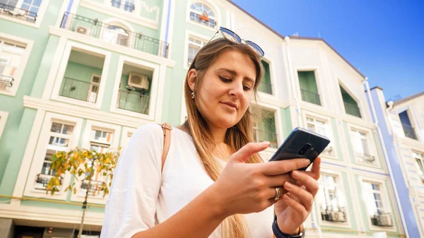 Portrét krásné usměvavé dívky na ulici města pomocí smartphonu — Stock fotografie