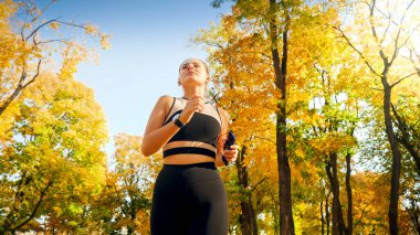 Gündoğumunda sonbahar parkında spor yapan ve koşan güzel seksi bir kadının portresi.