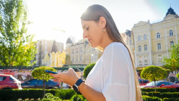 Retrato de una joven mujer ocupada caminando por la calle y escribiendo el mensaje en el teléfono inteligente —  Fotos de Stock