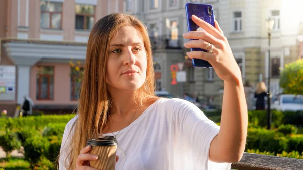 Πορτρέτο fo stylish νεαρή γυναίκα κάνει αυτο πυροβόλησε στο κινητό τηλέφωνο στον πάγκο στο πάρκο — Φωτογραφία Αρχείου