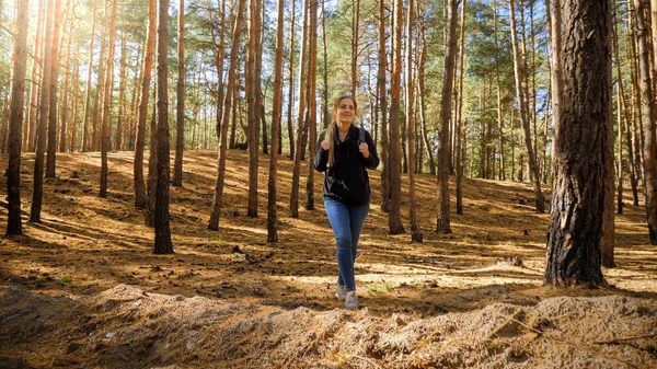 Young woman with big tourists bag hiking on the path through pine forest — Stock Photo, Image