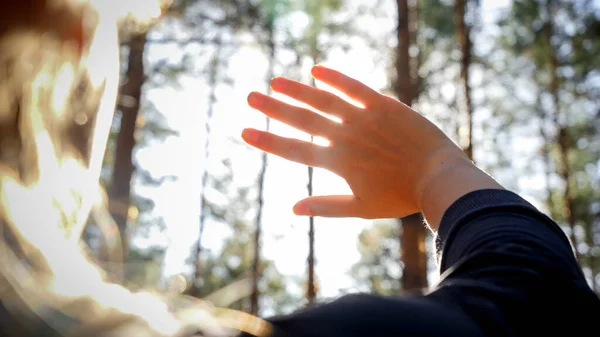 Närbild foto av ung kvinna ser ljus sol genom fingrarna i skogen — Stockfoto