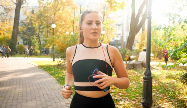 Toned portret van jonge mooie vrouw joggen in de herfst park in de ochtend — Stockfoto