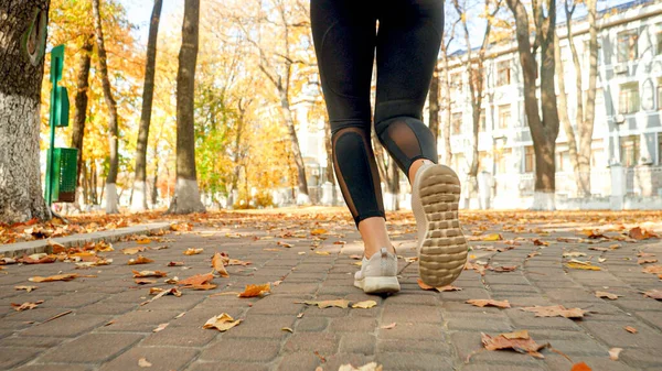 Closeup photo of female feet in sneakers jogging in autumn park — Stock Photo, Image