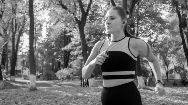 Black and white portrait of beautiful young woman jogging in autumn park — Stock Photo, Image