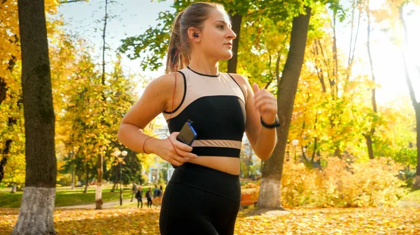 Portrait of beautiful sexy woman doing fitness and jogging at autumn park — Stock Photo, Image