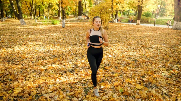 Beautiful young woman in leggings running and trainin in autumn park — Stock Photo, Image