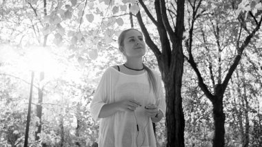 Sunny Park 'ta kulaklıklı, gülümseyen genç bir kadının siyah beyaz fotoğrafı.