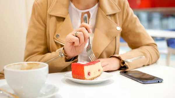Imagen de cerca de una mujer joven comiendo pastel dulce con tenedor en la cafetería — Foto de Stock